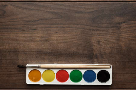 box of paints and a brush on the wooden tableの写真素材