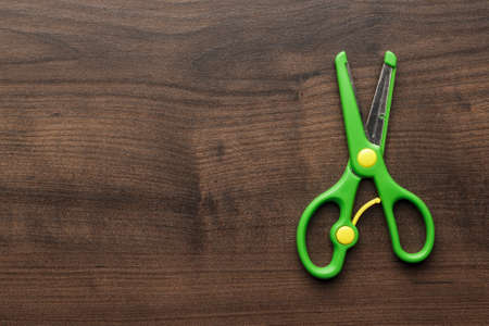 children's scissors on the brown wooden tableの写真素材