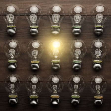 glowing bulb uniqueness concept on brown woodentableの写真素材