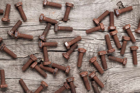 old rusty screw bolts on the wooden table backgroundの写真素材