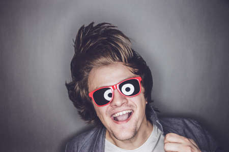 casual young man with sunglasses shaking his headの写真素材