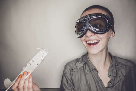 short-haired girl in retro pilot glasses with wooden planeの写真素材