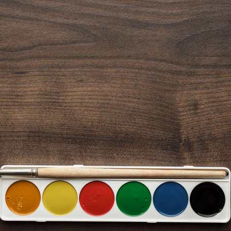 box of paints and a brush on the wooden tableの写真素材