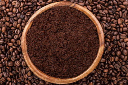 coffee beans and wooden bowl full of ground coffee on the table backgroundの写真素材