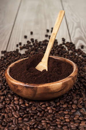 coffee beans and wooden bowl full of ground coffee on the table backgroundの写真素材