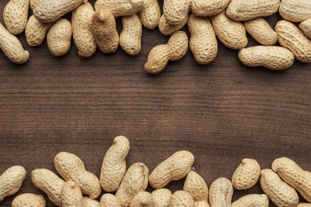 many roasted peanuts on the wooden table background with copy space