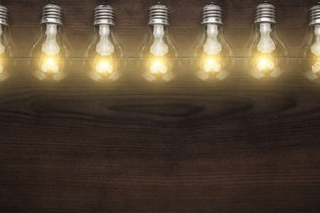glowing bulbs over wooden background with copy spaceの写真素材