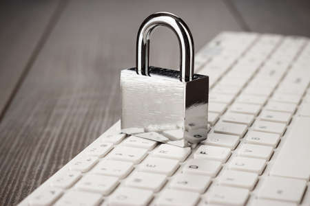 padlock and white computer keyboard on the wooden office table. privacy protection, encrypted connection conceptの写真素材