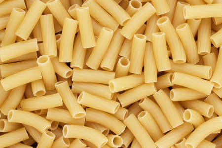 close-up of dry uncooked tortiglioni pasta on the table texture background