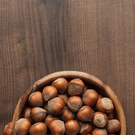 hazelnuts in wooden bowl on the brown table backgroundの写真素材