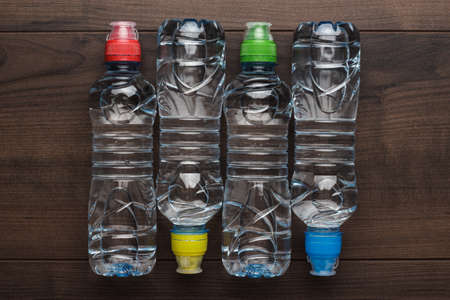 plastic water bottles with caps of different colour on the wooden tableの写真素材