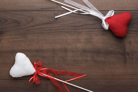red and white plush heart shapes on sticks over wooden backgroundの写真素材