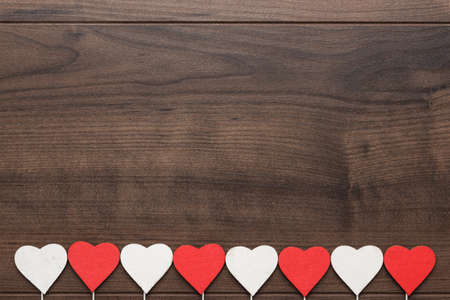 red and white heart shapes on sticks over wooden backgroundの写真素材