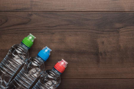 plastic water bottles with caps of different colour on the wooden tableの写真素材