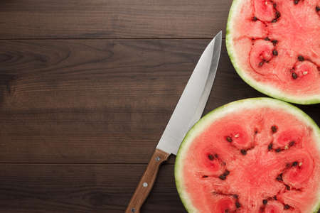 half of watermelon and knife on the wooden tableの写真素材