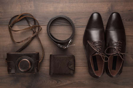 brown shoes, purse, belt, and film camera on wooden table