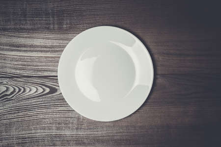 white plate on the wooden brown tableの写真素材