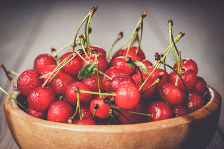 wooden bowl full of cherries on the tableの写真素材