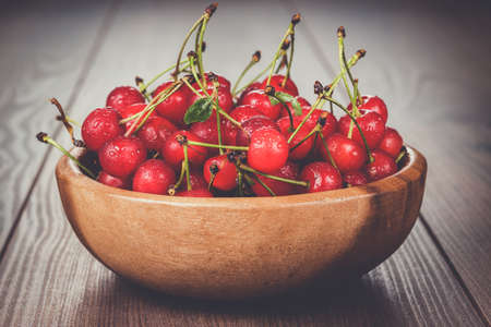 wooden bowl full of cherries on the tableの写真素材