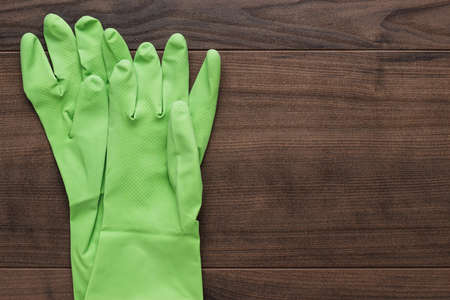 green rubber cleaning gloves on wooden backgroundの写真素材