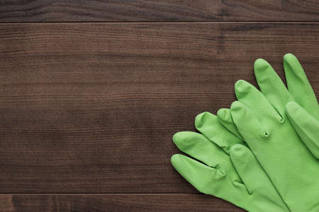 green rubber cleaning gloves on wooden backgroundの写真素材