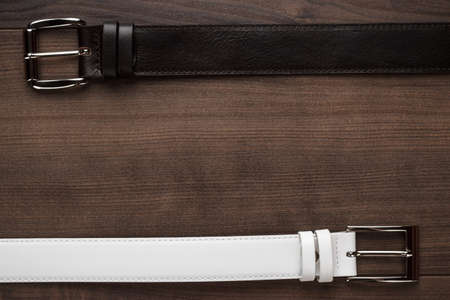 brown and white men's leather belts on wooden tableの写真素材