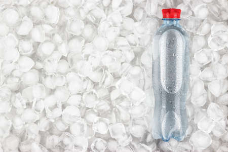 plastic water bottle with red cap is cooling in the iceの写真素材