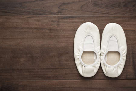 child's white dancing shoes on the wooden floorの写真素材
