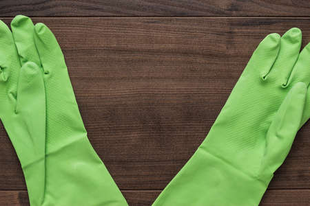 green rubber cleaning gloves on wooden backgroundの写真素材