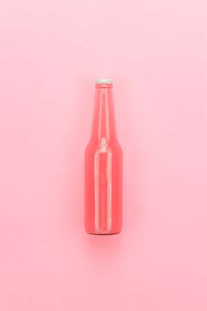 glass bottle of pinkish soda drink on pink backgroundの写真素材