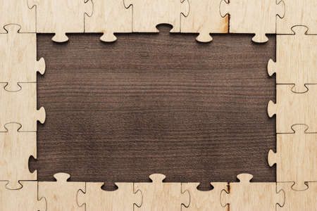frame of puzzle pieces on brown wooden tableの写真素材