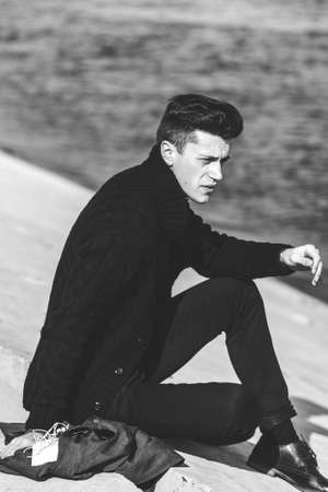 handsome young man in sitting near waterの写真素材