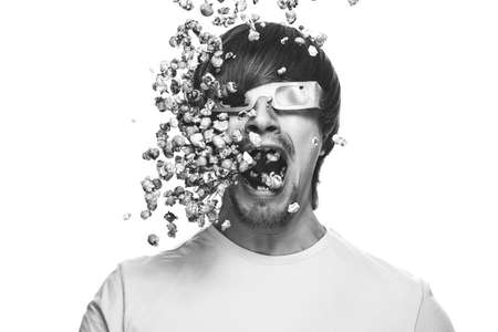 3d technology conceptual photo of young man in stereo glasses eating popcornの写真素材