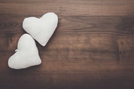 two knitted heart shapes on the wooden tableの写真素材
