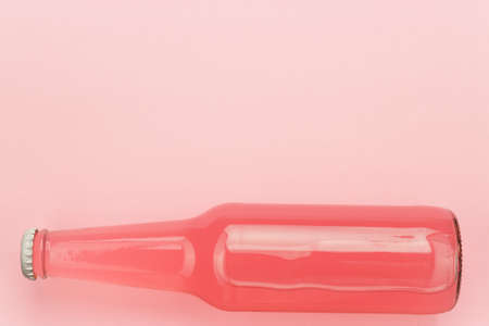 glass bottle of pinkish soda drink on pink backgroundの写真素材