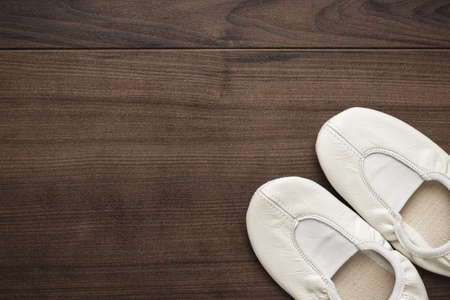 childs white dancing shoes on the wooden floorの写真素材