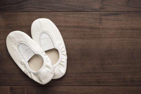 childs white dancing shoes on the wooden floorの写真素材
