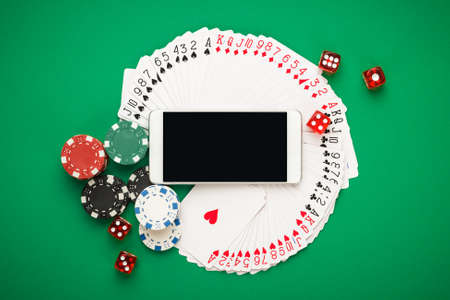 online casino concept, playing cards, dice chips and smartphone with copyspace on the green table. view from above. banner template layout mockup for online casinos and gambling.の写真素材
