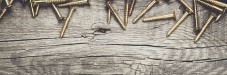 new yellow screws on the wooden table backgroundの写真素材