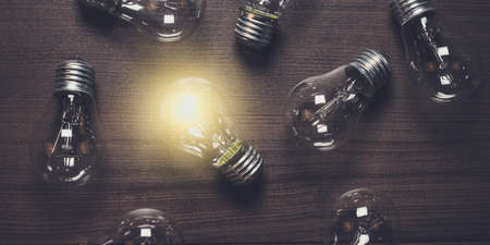 glowing bulb over wooden background uniqueness conceptの写真素材
