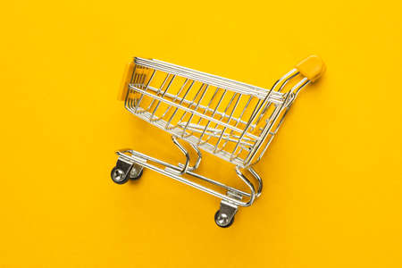 close-up of shopping trolley on yellow background with some copy spaceの写真素材