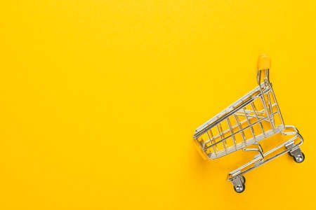 shopping trolley on yellow background with some copy space