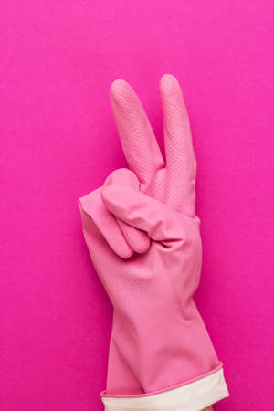 hand in pink protective glove shows v sign. meaning that everything clean now and victory over dirtの写真素材