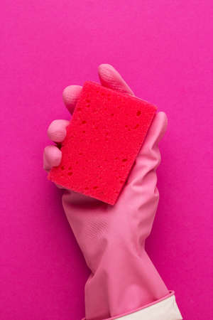 hand in protective glove holding red sponge over purple backgroundの写真素材