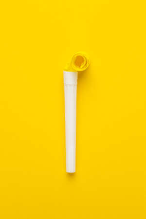 paper and plastic party horn on the yellow background