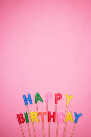 colorful letter-shaped happy birthday candles on pink backgroundの写真素材