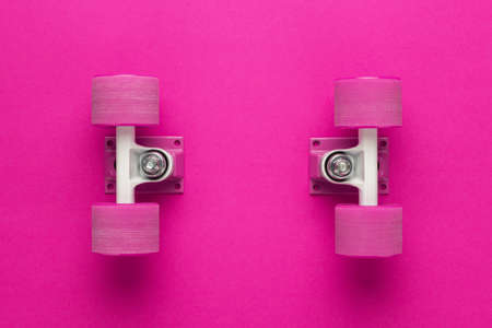 cruiser skateboard trucks and wheels on deep pink with background copy space