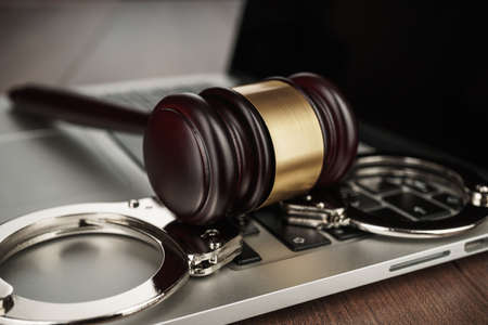 handcuffs and judge gavel on computer cyber crime conceptの写真素材