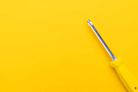 close-up of manual screwdriver with plastic handle on the yellow backgroundの写真素材