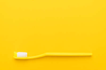 close-up plastic toothbrush on the yellow background with copy spaceの写真素材